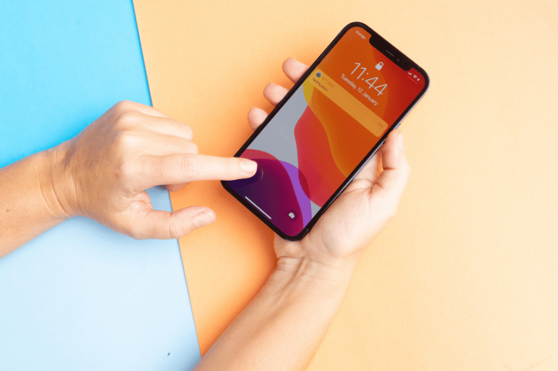 Hand holding iPhone displaying colorful mobile app interface -